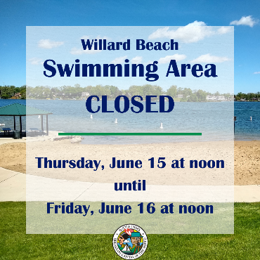 Small beach on lake with pavilion and sidewalk 