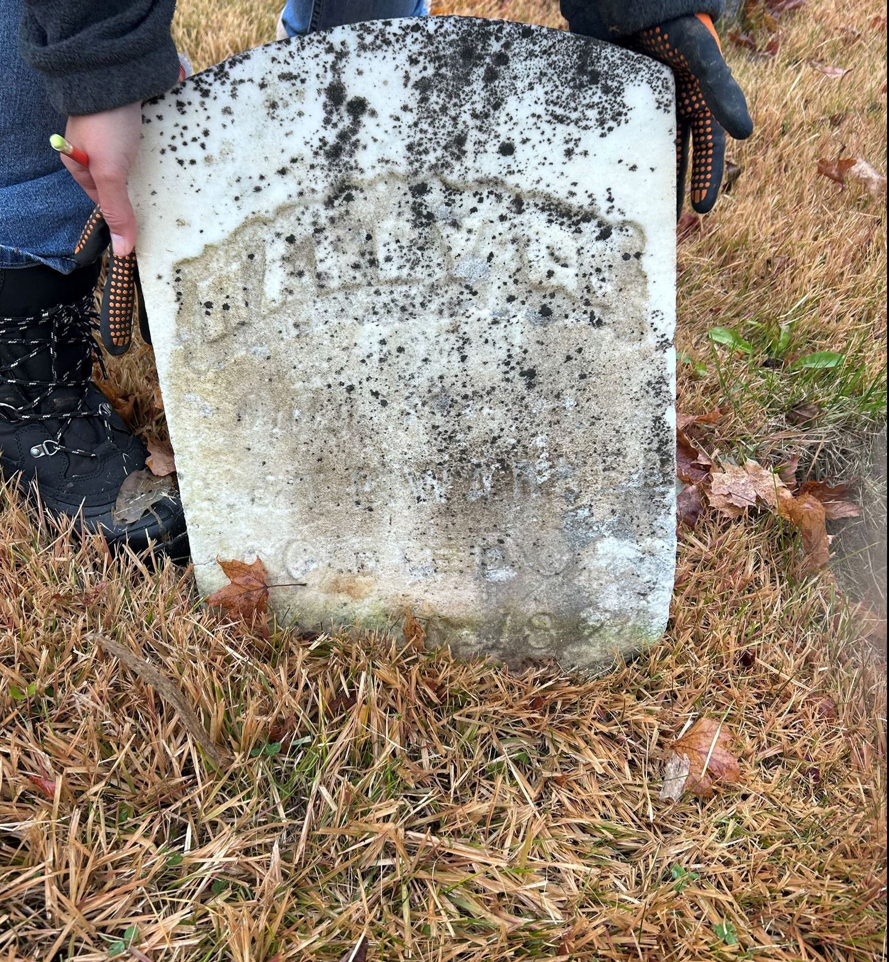 Photo of broken headstone being held up by clerk staff - Beckley Cemetery