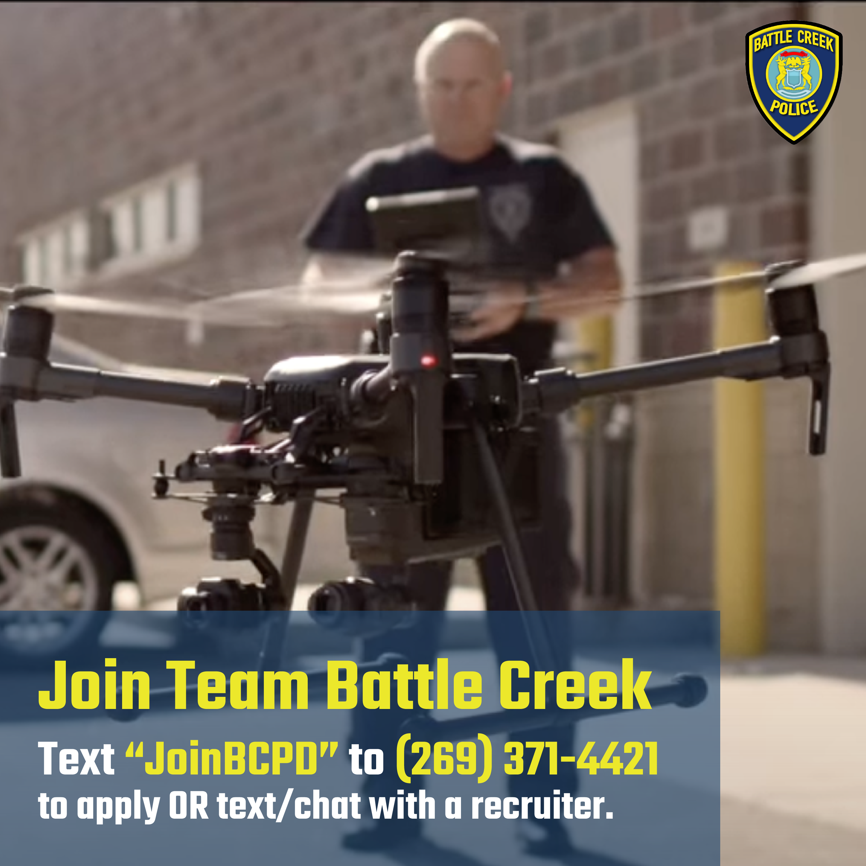 Blurred background image of bald man in dark police uniform, flying a drone.