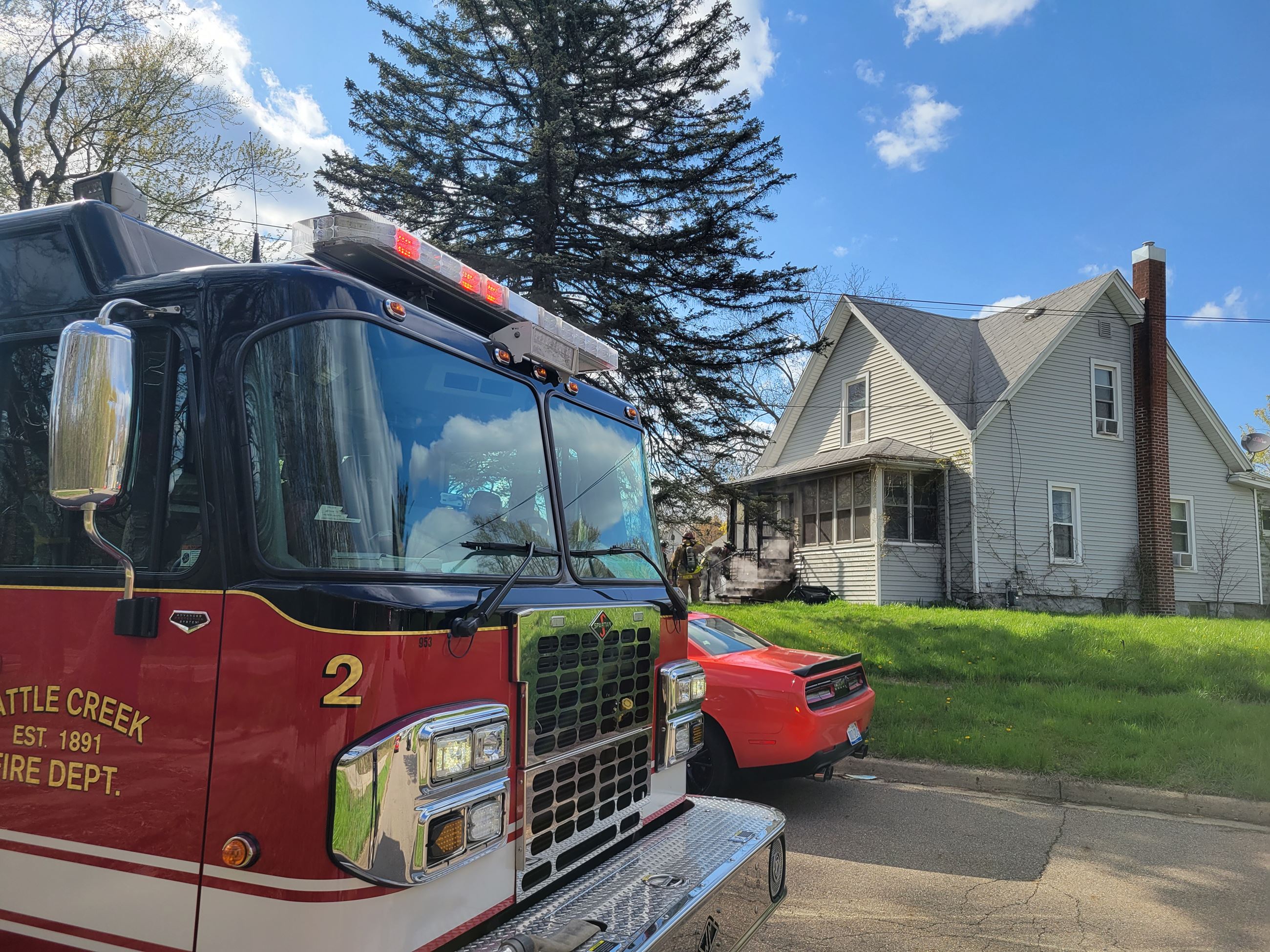 Fire vehicle and car parked on a street with a house in the background
